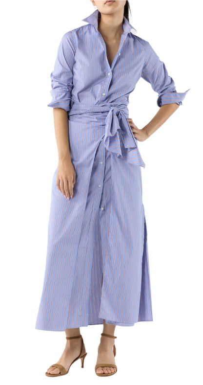 A woman wears the Ann Mashburn Maxi Tie-Waist Shirtdress in blue and white stripes with rolled sleeves and beige heeled sandals.