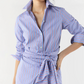 A person wearing the Ann Mashburn Maxi Tie-Waist Shirtdress, featuring blue Italian poplin with red and white stripes, a turned-up collar, rolled sleeves, and a matching waist tie for a flattering silhouette.