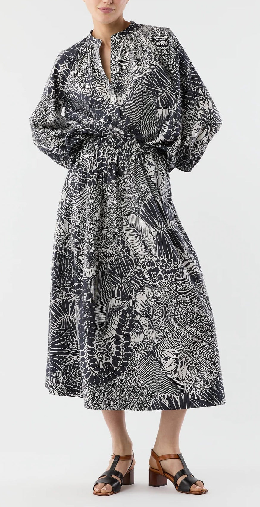 A person wearing the Ann Mashburn Sienna Block Print Top, featuring a black and white abstract botanical print, styled with black heeled sandals for a refined romantic look.