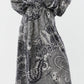 A person wearing the Miranda Block Print Skirt by Ann Mashburn, paired with black heeled sandals, stands against a white background.