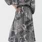 A person stands with one hand on their hip, wearing the Ann Mashburn Sienna Block Print Top and brown sandals.