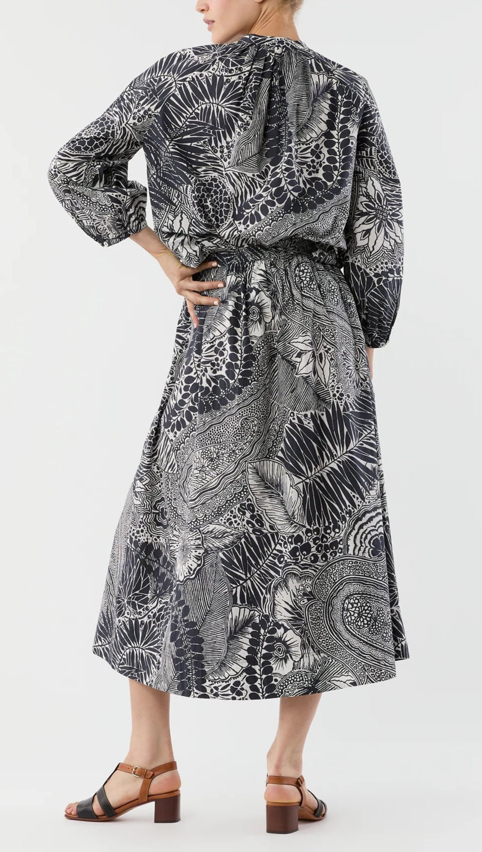 A person stands with one hand on their hip, wearing the Ann Mashburn Sienna Block Print Top and brown sandals.