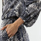 A person wearing the Ann Mashburn Sienna Block Print Top, a long-sleeved romantic style with a monochrome botanical pattern, shown from neck to mid-thigh with one hand in a pocket.