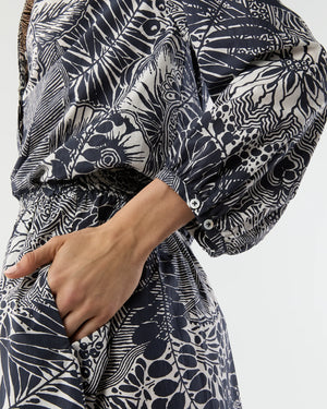 A person wearing the Ann Mashburn Sienna Block Print Top, a long-sleeved romantic style with a monochrome botanical pattern, shown from neck to mid-thigh with one hand in a pocket.
