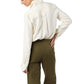 A person stands with their back turned, wearing the Ann Mashburn Hannah Blouse tucked into high-waisted olive green pants.