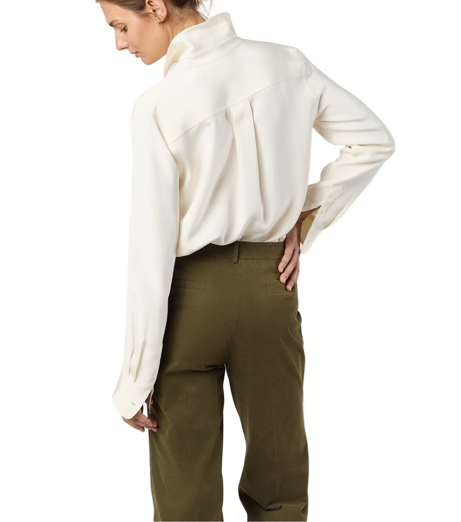 A person stands with their back turned, wearing the Ann Mashburn Hannah Blouse tucked into high-waisted olive green pants.