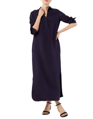 A woman wears the Ann Mashburn Piper Maxi Dress, a long-sleeve, collared, ankle-length crepe de chine dress with a front slit, styled with black sandals.