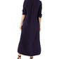 A woman stands with her back to the camera, wearing an ankle-length, lightweight dark purple Piper Maxi Dress by Ann Mashburn with long sleeves and black heeled sandals.
