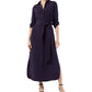 A woman wears the Ann Mashburn Piper Maxi Dress in lightweight dark purple, featuring a collar, belted waist, and side slit, paired with black strappy heels.