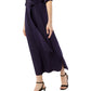 A person walks forward against a white background, wearing Ann Mashburn's long, dark purple Piper Maxi Dress in lightweight crepe de chine with a waist tie and black heeled sandals.