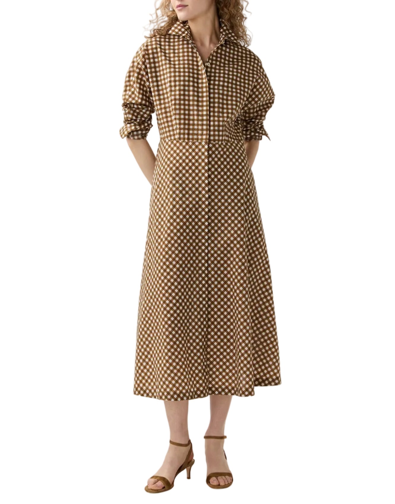 A person wearing the Charlie Shirtwaist Gingham Dress by Ann Mashburn, a brown and white checkered shirtdress with a collar and button-down front, paired with tan heeled sandals.