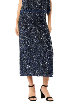 A person wearing the Ann Mashburn Ruby Beaded Mesh Skirt and black heeled sandals, shown from shoulders to feet against a white background.