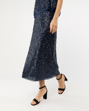 Person wearing the Ann Mashburn Ruby Beaded Mesh Skirt with a matching top and black block-heeled sandals, standing against a plain white background.