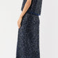 A woman stands against a white background wearing Ann Mashburn's Ruby Beaded Mesh Skirt paired with a sleeveless navy sequin top and black ankle-strap block heel sandals.