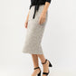 A woman stands against a plain background wearing the Ann Mashburn Sequin Pull-On Skirt with a black long-sleeve top and black ankle-strap block heel sandals.