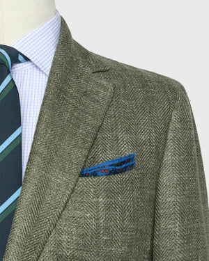 Mannequin dressed in the Sid Mashburn Ghost Blazer—an Italian hopsack jacket—paired with a blue and green striped tie, light blue checkered shirt, and blue patterned pocket square; a stylish, lightweight choice for any occasion.