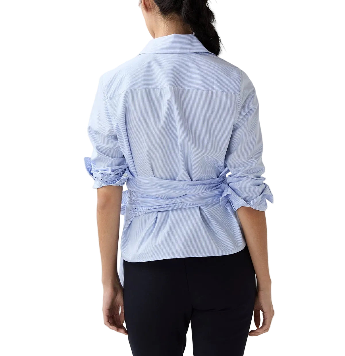 A woman stands with her back to the camera, wearing the Ann Mashburn Hilary Wrap Small Bengal Top—a light blue blouse with tied sleeves and self-tie belt—paired with black pants, on a white background.
