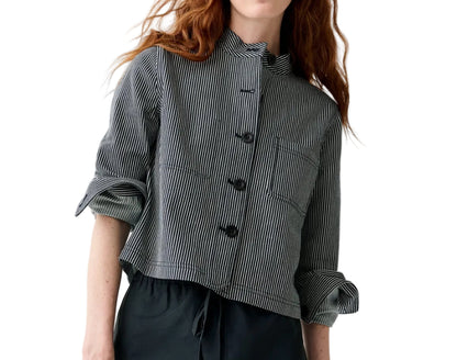 A person wears the Ann Mashburn Short Chore Jacket in black and white railroad stripes, styled with black pants.