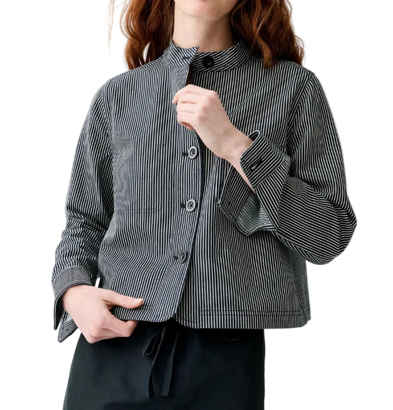 A person wears the Ann Mashburn Short Chore Jacket over a black and white vertically striped button-up shirt with long sleeves and black pants, standing against a white background.