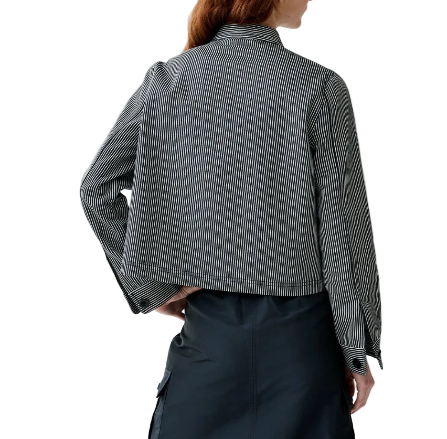 A person shown from the back wearing an Ann Mashburn Short Chore Jacket in black and white vertical stripes, paired with a dark skirt.