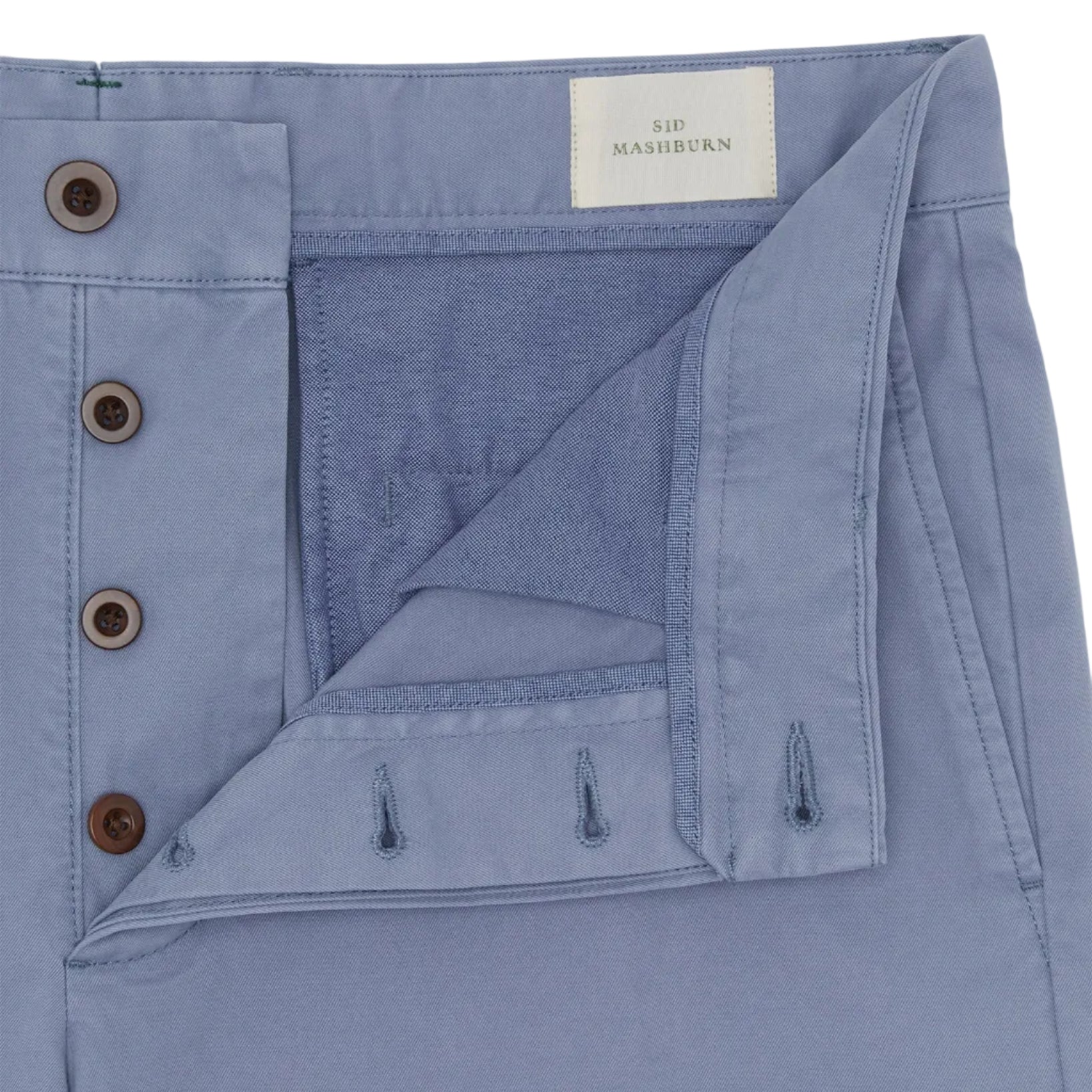 Close-up of light blue Garment Dyed Field Pant by Sid Mashburn, featuring an open fly with brown buttons and a branded label inside the waistband.