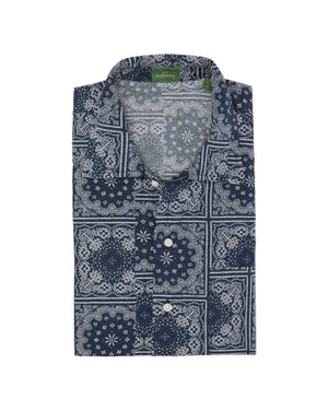 Sid Mashburn Ripley Shirt—an updated nod to the classic 1950s vacation shirt, this long-sleeve, patchworked paisley shirt features a blue and white bandana print, button front, and visible green tag inside the collar.