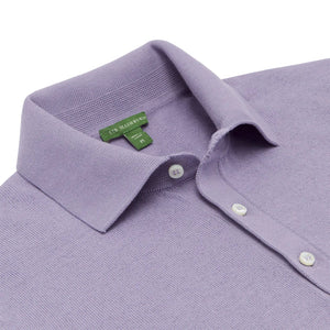 A neatly folded lavender Sid Mashburn Short-Sleeved Rally Polo Sweater in a slim fit, featuring white buttons.
