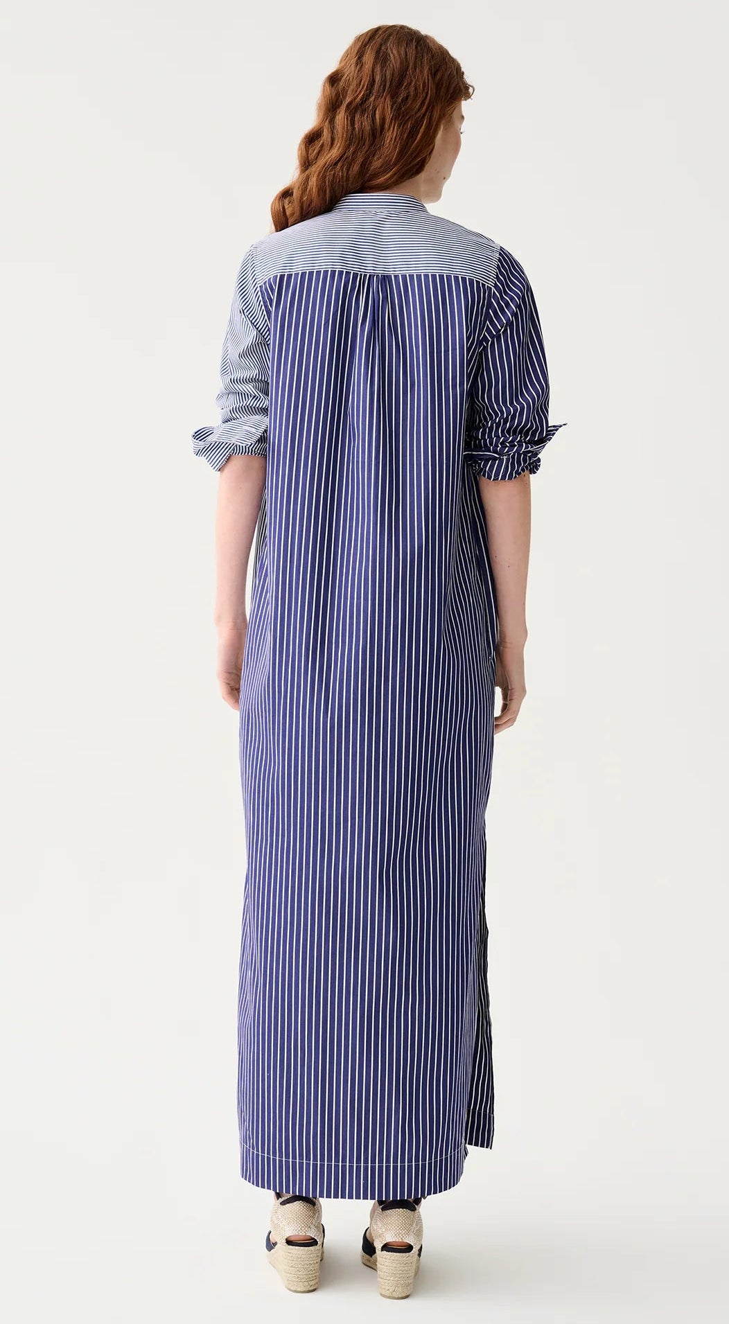 A person with long, wavy brown hair is shown from the back wearing the Ann Mashburn Mandarin Talitha Mixed Stripe Poplin Shirtdress and platform sandals.