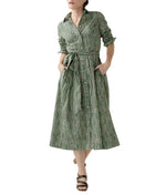 A woman wears the Ann Mashburn Classic Shirtwaist Floral Stripe Dress, featuring long sleeves, a collar, and a belt, styled with black sandals.
