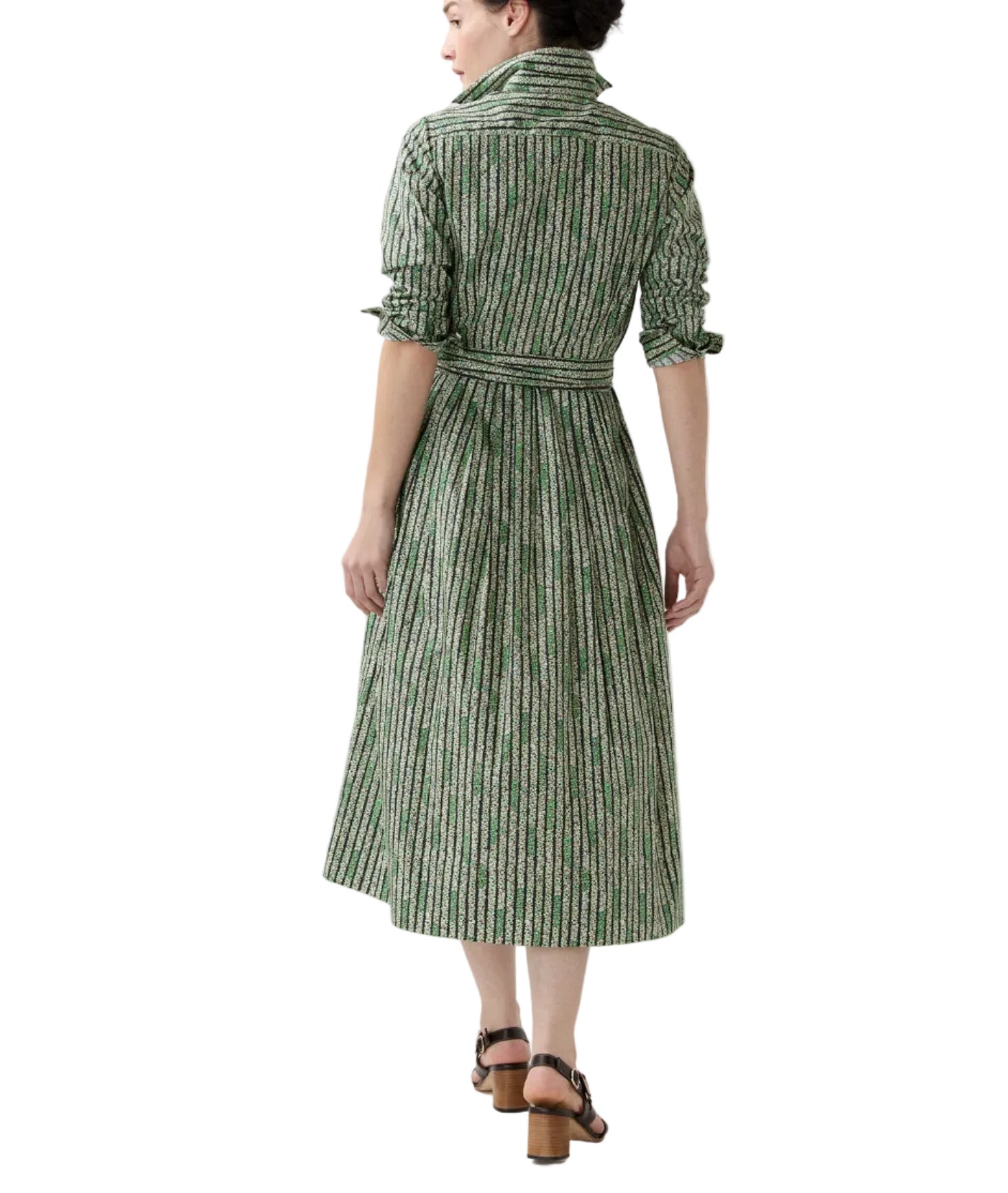 A woman faces away, wearing the Ann Mashburn Classic Shirtwaist Floral Stripe Dress with a belt and brown heeled sandals.