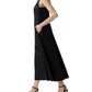 A woman stands in profile with her hands in the pockets of the Ann Mashburn Rosalind Dress, a sleeveless black poplin style, paired with black heeled sandals.