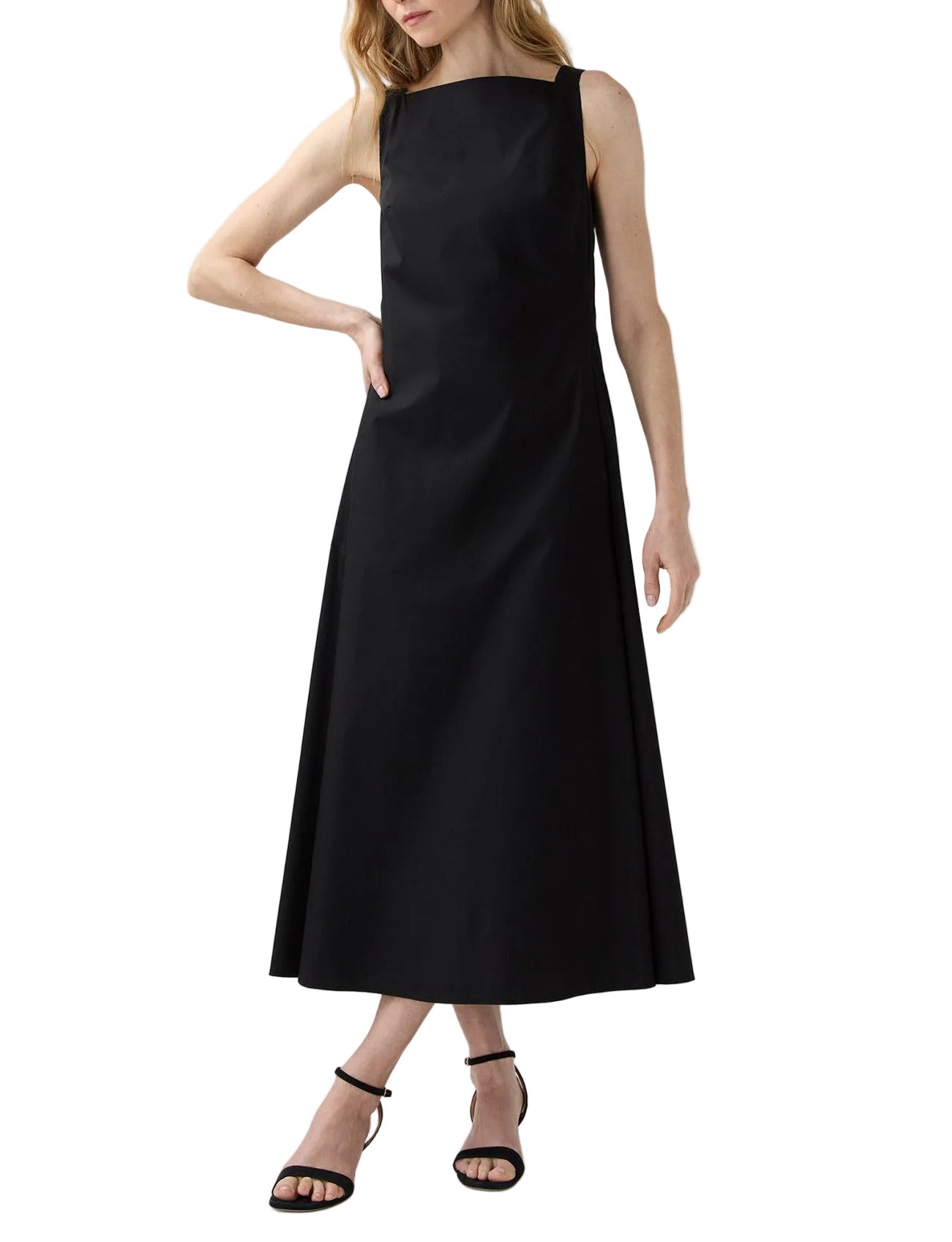 A woman in the Ann Mashburn Rosalind Dress, a sleeveless black poplin style falling to the ankle, pairs it with black strappy heels while standing against a white background.