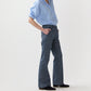 Person wearing a light blue button-up shirt with rolled-up sleeves, Ann Mashburn Lane Cotolino Chambray Pant, and black shoes, standing against a plain white background.