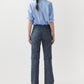 Person standing facing away, wearing high-waisted Lane Cotolino Chambray Pant by Ann Mashburn and a light blue button-up shirt with rolled sleeves against a plain background.