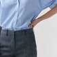 Person wearing Ann Mashburn’s Lane Cotolino Chambray Pant, paired with a light blue button-up shirt tucked in, standing with one hand resting on their hip.