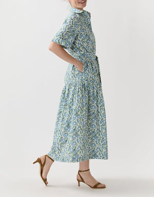 A person wearing the Ann Mashburn Nathalie Vigers' Vine Liberty Dress with short sleeves and tan heeled sandals, standing sideways against a plain white background.