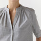 A person wears the Ann Mashburn Sage Blouse, a collared, long-sleeve poplin top with a small black and white check pattern, shown from shoulders to mid-torso against a plain background.
