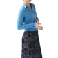 A woman wearing the Ann Mashburn Connor Cotton/Silk Sweater in light blue and a dark floral skirt stands against a white background.