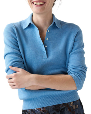 A woman wears the Ann Mashburn Connor Cotton/Silk Sweater in light blue and a dark patterned skirt, arms crossed and smiling.