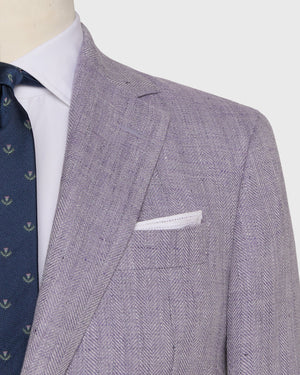 A close-up of a person wearing the Sid Mashburn Kincaid No. 2 Jacket in light purple herringbone cloth, paired with a white dress shirt, navy patterned tie, and a white pocket square.