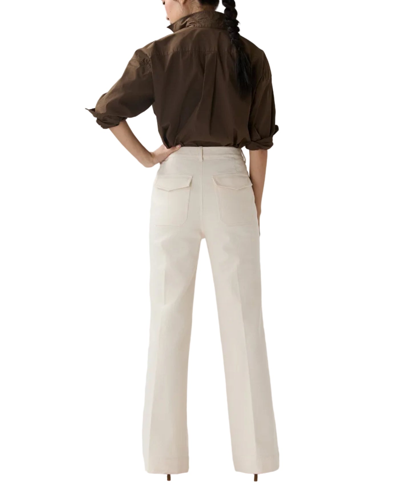 A woman faces away, wearing a brown long-sleeve shirt with rolled sleeves and cream Camille Patch-Pocket Stretch Jeans by Ann Mashburn.