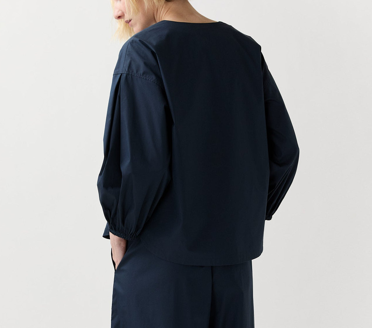Person wearing the Ann Mashburn Meghan Top—a loose-fitting, long-sleeve navy blouson—paired with matching wide leg pants, shown from the back against a plain light background.