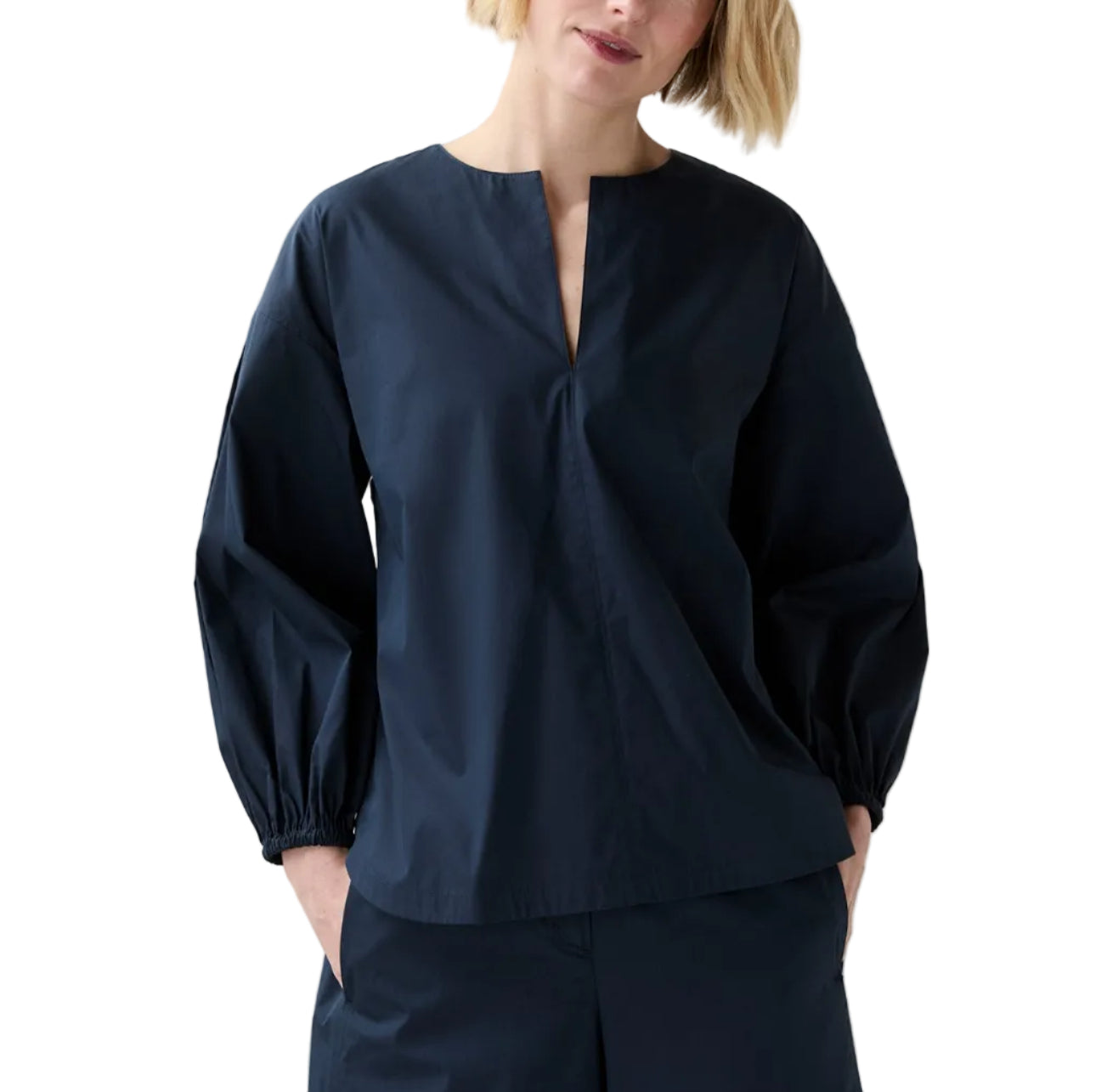 Someone wearing the Ann Mashburn Meghan Top, a dressy nylon blouson with a split neckline, paired with matching wide leg pants and standing with hands in pockets.