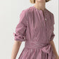 A person wearing the Ann Mashburn Felicity Shirtwaist Dress featuring red-and-white vertical stripes and a waist tie, standing against a plain light background.