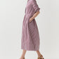 A person wearing the Ann Mashburn Felicity Shirtwaist Dress—long-sleeved, red and white striped with pockets—and tan heeled sandals, standing against a plain white background.
