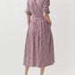 Person wearing the Ann Mashburn Felicity Shirtwaist Dress, a red and white bengal-striped poplin midi dress with a belted waist, shown from the back.