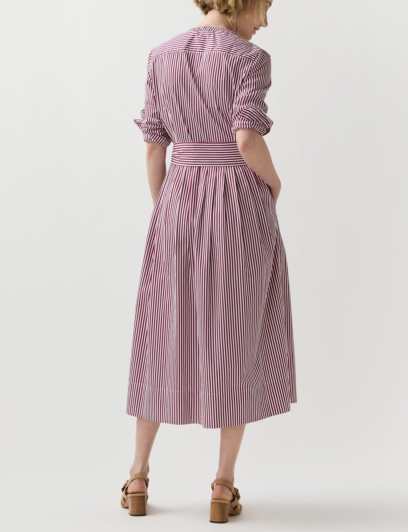 Person wearing the Ann Mashburn Felicity Shirtwaist Dress, a red and white bengal-striped poplin midi dress with a belted waist, shown from the back.