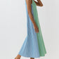 A woman wearing the Lise Maxi Dress by Ann Mashburn—a sleeveless, ankle-length A-line dress in striped Italian poplin with blue and green vertical stripes and a square neckline—pairs it with brown sandals against a plain white background.