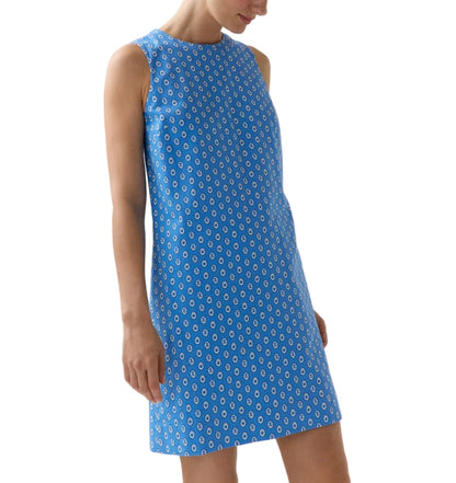 A woman wears the Ann Mashburn Susy Shift Dress—a sleeveless, knee-length blue 1960s A-line dress with a white circular pattern—while standing against a white background.