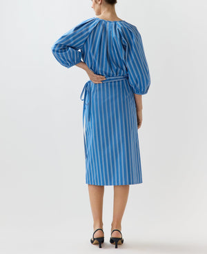 A woman stands facing away, wearing the Ann Mashburn Morgan Variegated Stripe Skirt with black heeled sandals.